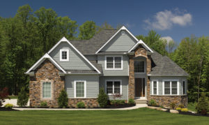 Suburban home with green lawn, stone facade and green siding 