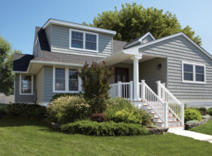 Home with a green lawn, white railing and front steps, and grey vinyl siding 