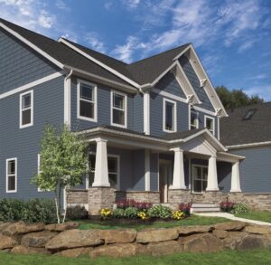 Suburban home with columns, stone wall, and blue vinyl siding 